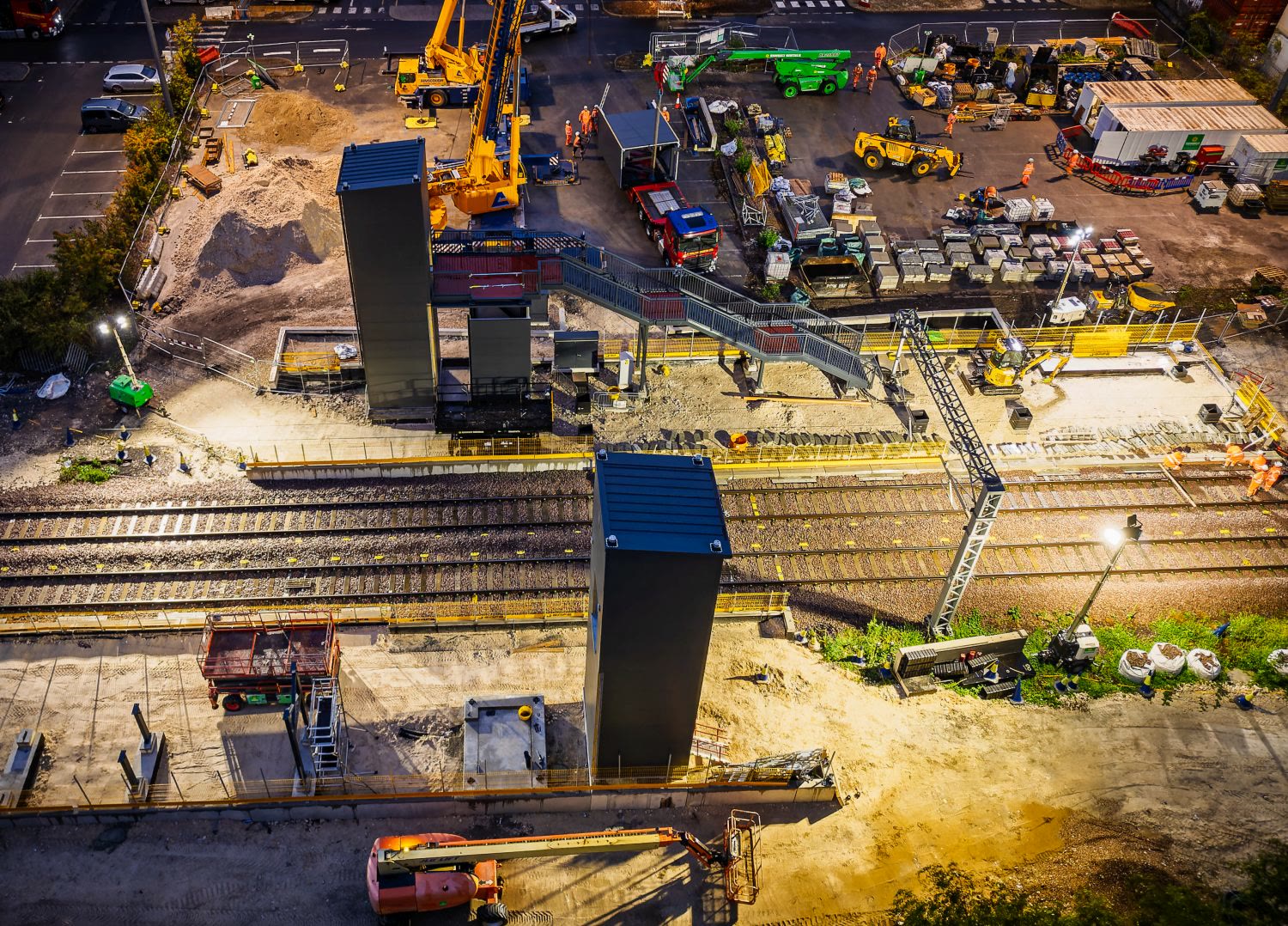 Aerial night view of the site showing cranes and structures across the rail platform